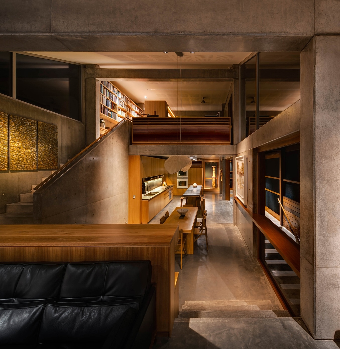 Modern, multi-level interior with concrete walls, wooden accents, open shelving, and dim lighting creating a cozy ambiance.